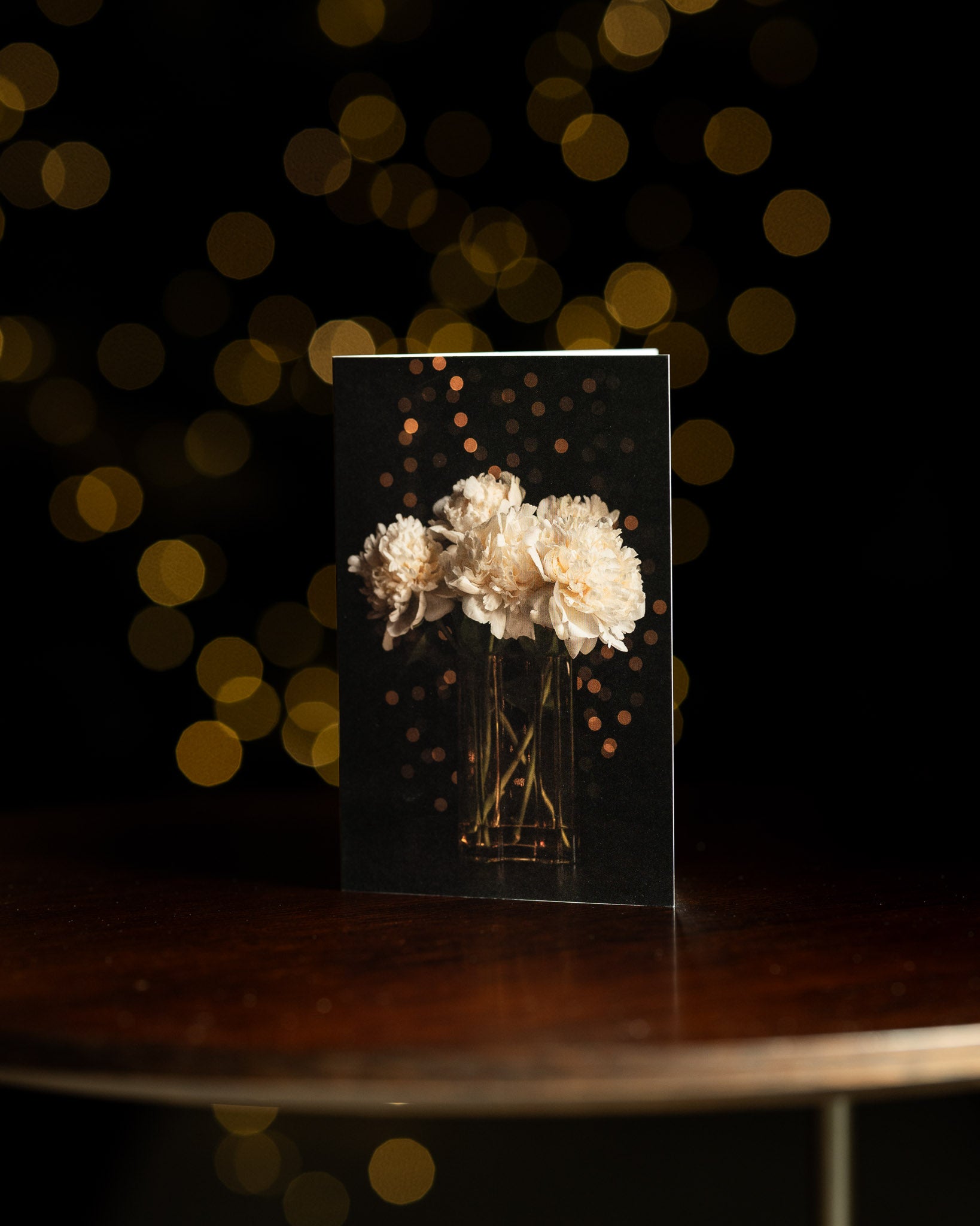 Christmas card with a vase of white peonies and fairy lights